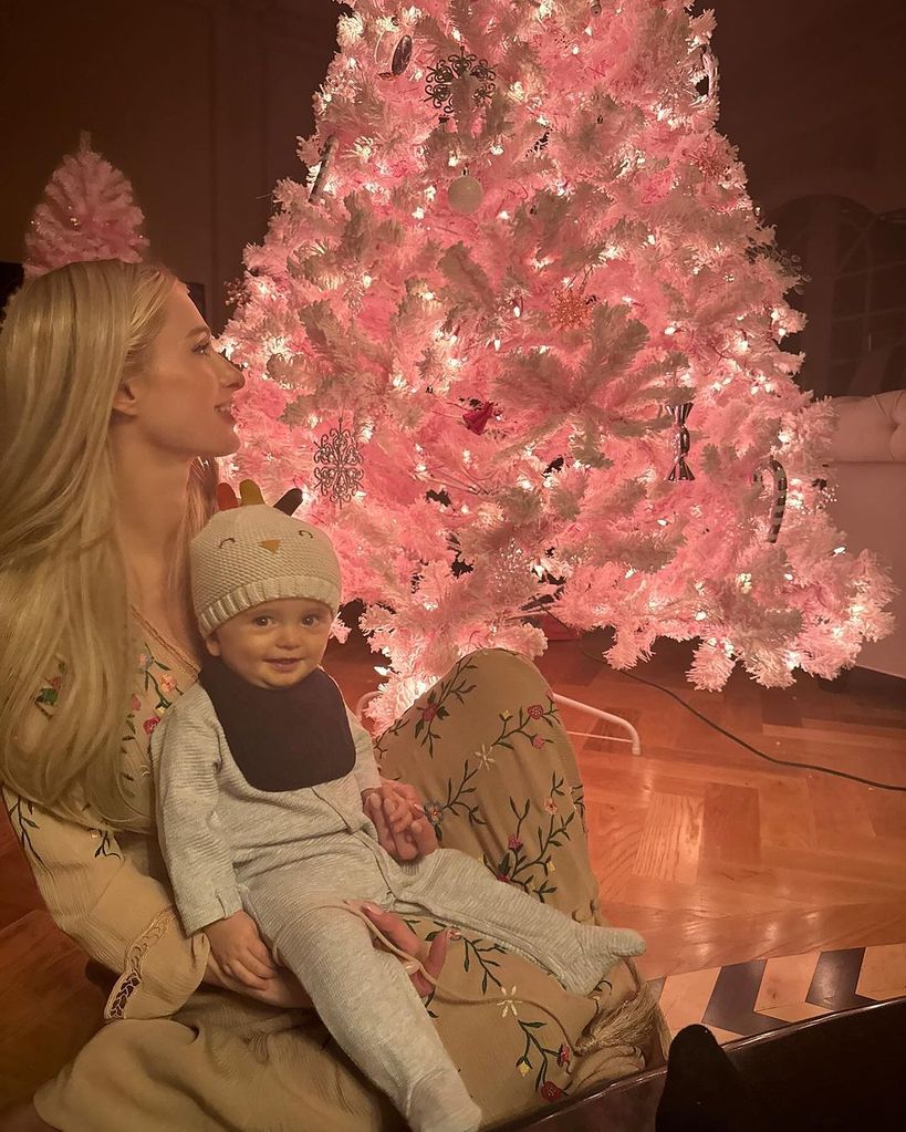 Paris Hilton and her son Phoenix sit beside a pink Christmas tree inside their family home