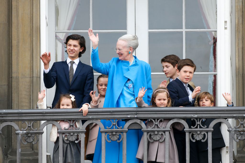 Members of the Danish royal family waving on a balcony 