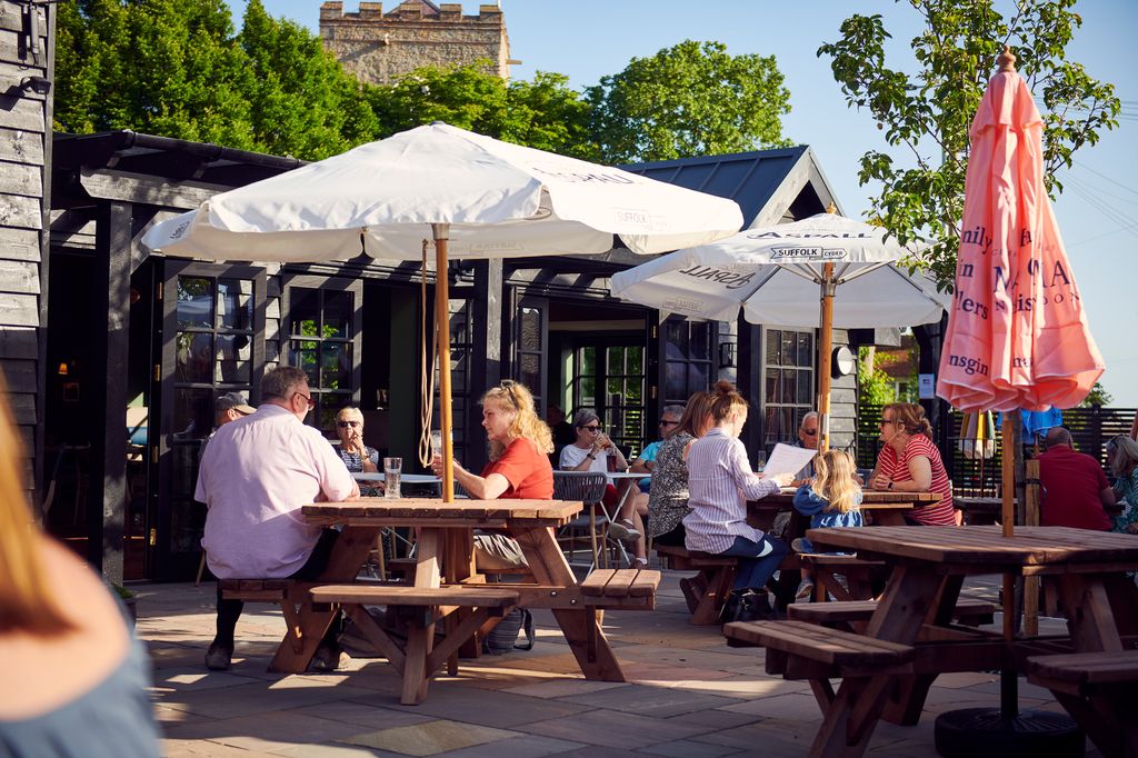 White Hart Inn terrace bathed in sunlight with people drinking at wooden tables