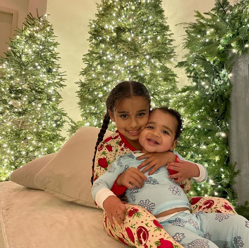 Two children in Christmas pyjamas surrounded by Christmas trees
