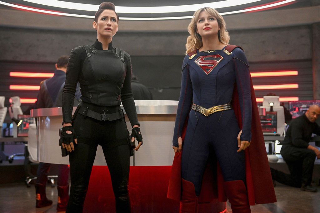 woman dress in black next to woman in supergirl costume
