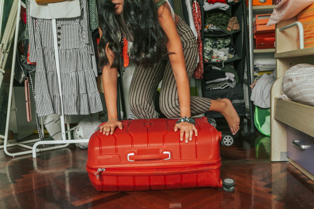 latina young woman packing luggage for  holidays in her bedroom