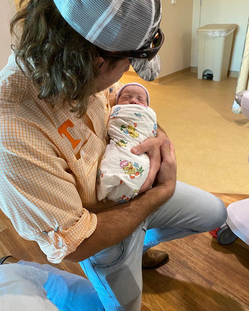 man in a cap holding a tiny baby