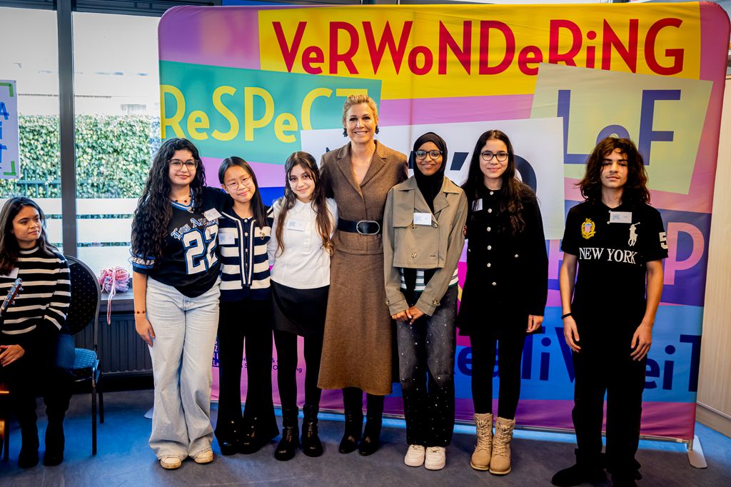 Queen Maxima in skirt set and black boots in classroom in line up with students