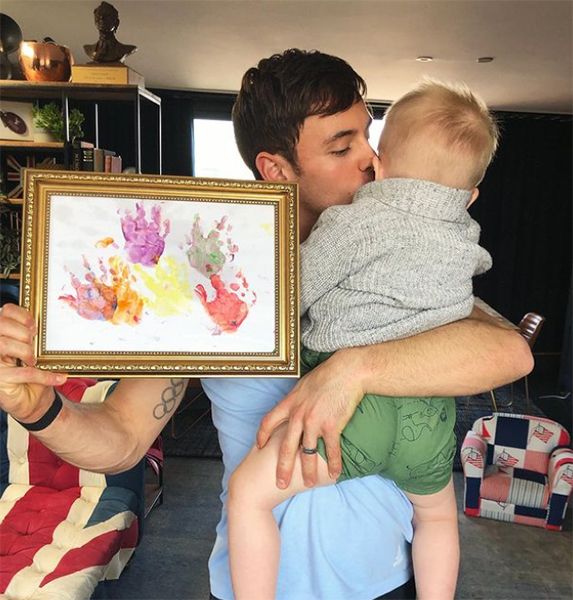 Tom Daley holding son and hand painting