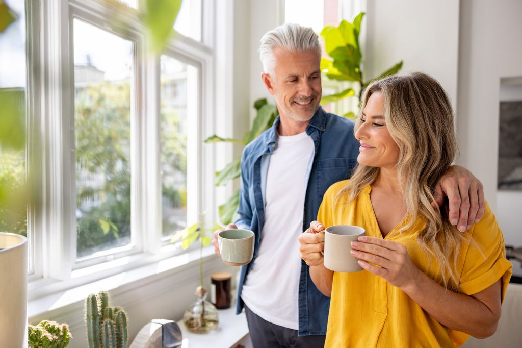 Happy couple at home drinking a cup of coffee in the morning and smiling - domestic life concepts