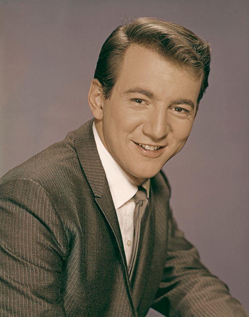 Bobby Darin sourit à la caméra en costume-cravate.