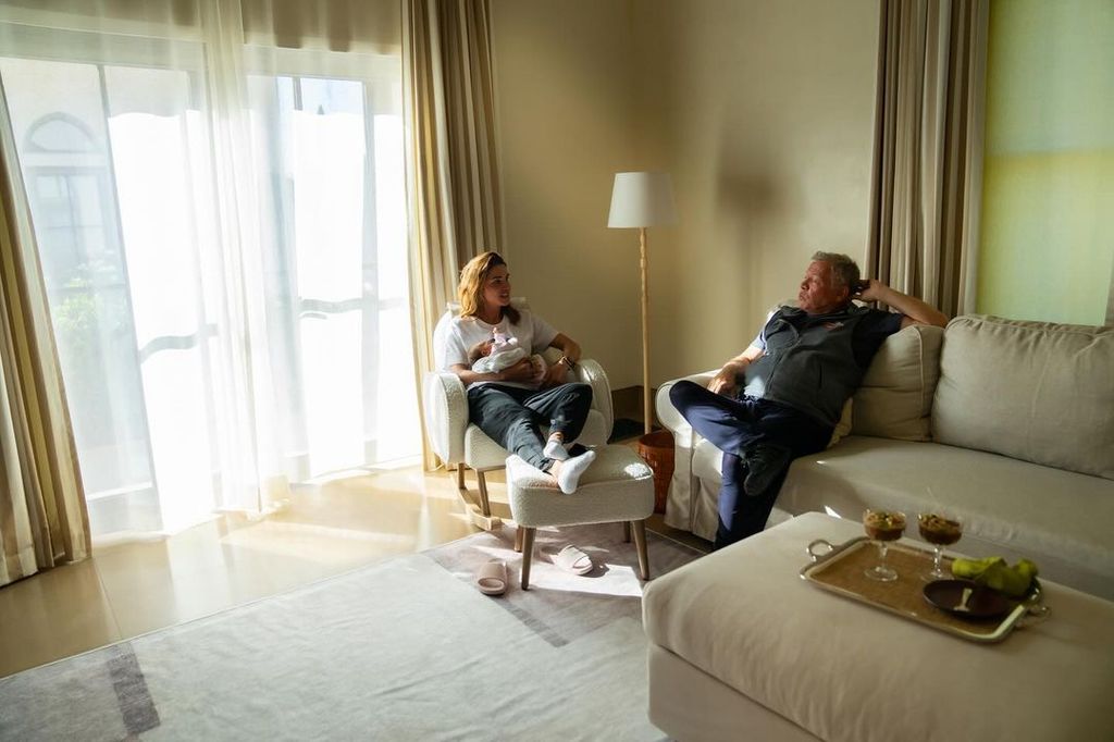 Queen Rania holding baby Iman on a white armchair