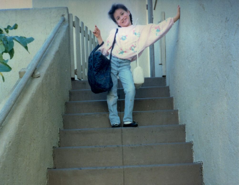 A young Meghan Markle posing with bags on a set of stairs