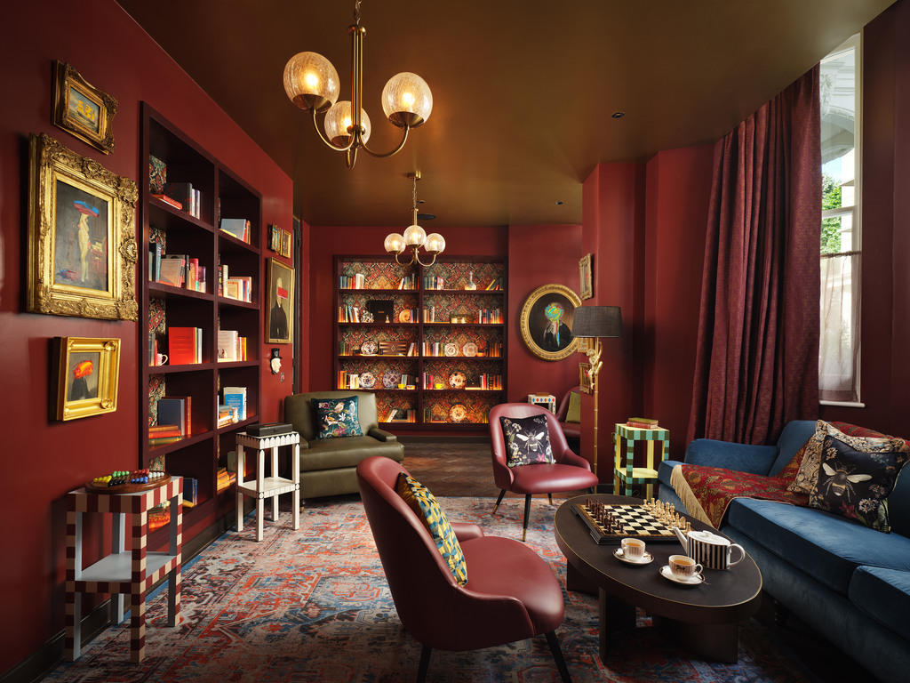 indoor library with red and burgundy furniture at The Other House in London