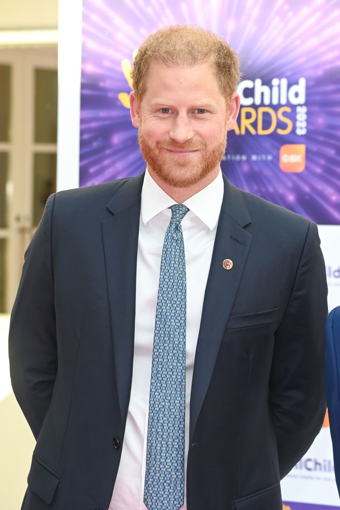 Prince Harry wearing a blue suit, smiling for the camera