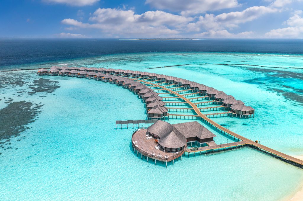 Tropical aerial landscape, seascape with pier, water bungalows villas with amazing sea lagoon beach. Exotic tourism destination, summer vacation background. Aerial travel