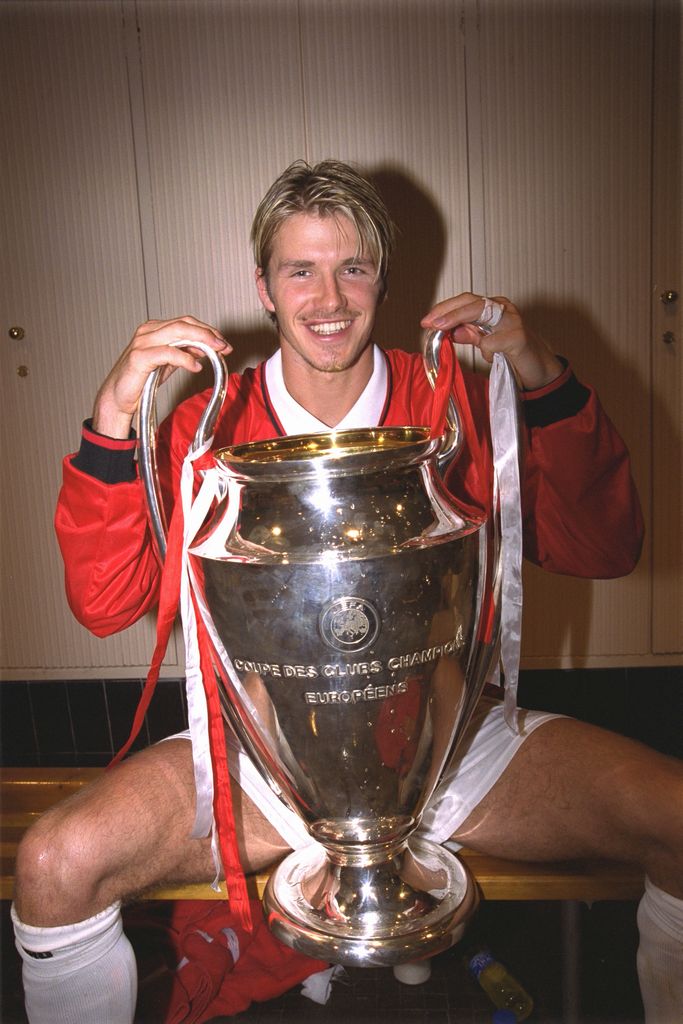 David beckham in dressing room holding football cup 