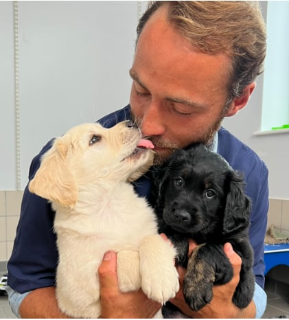 James Middleton kissing and cuddling two puppies