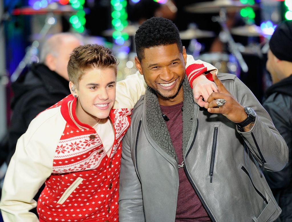 Justin Bieber with his arm around Usher smiling 