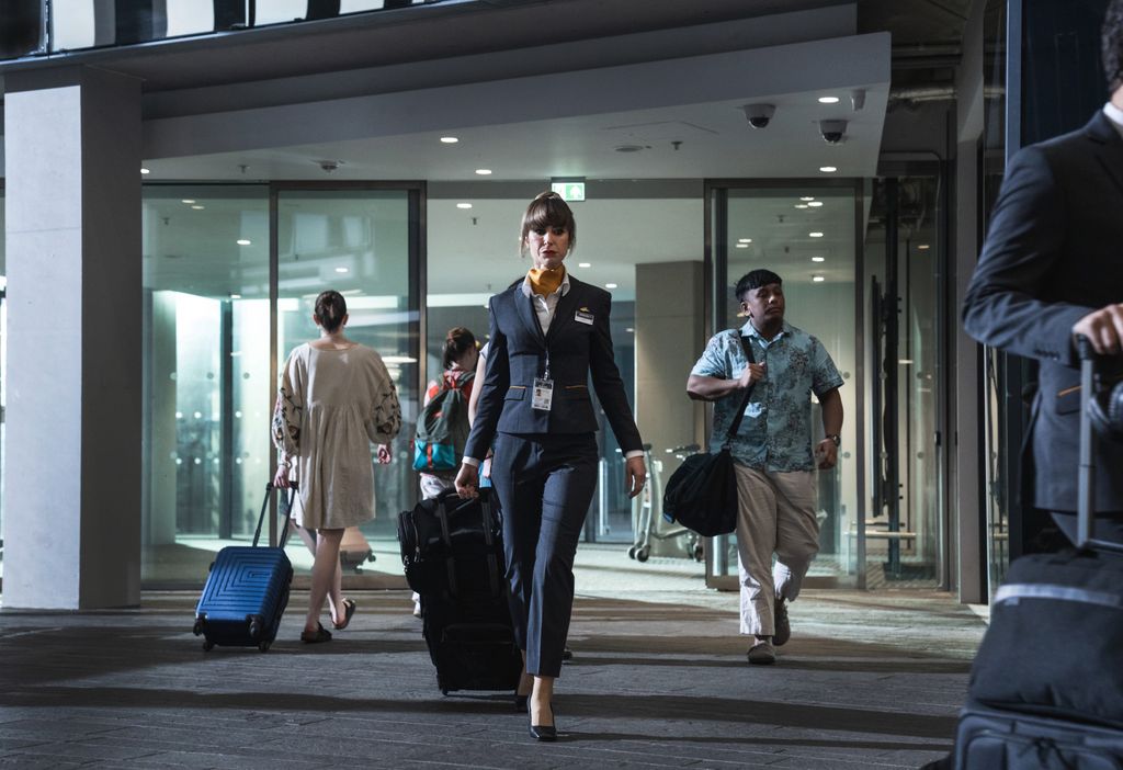 Flight attendant walking in airport with suitcase