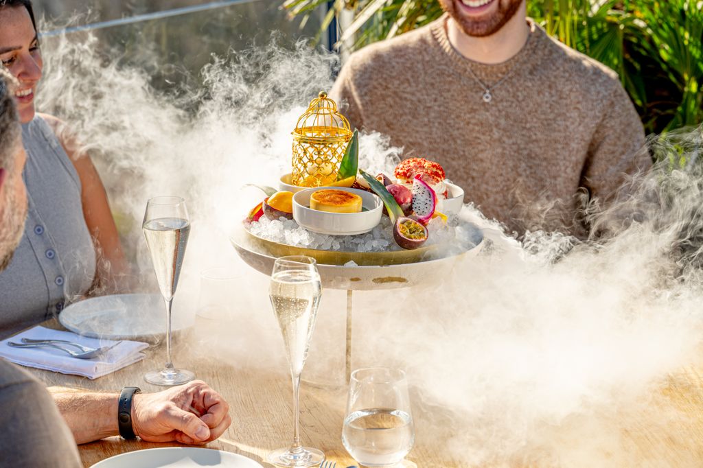 Desserts and drinks on a smoky table at the Aviary Rooftop Bar in London.
