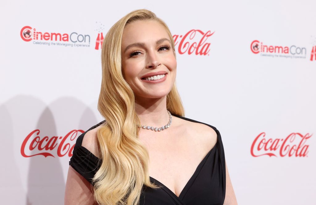 Lindsay Lohan with long blonde hair, wearing a black dress