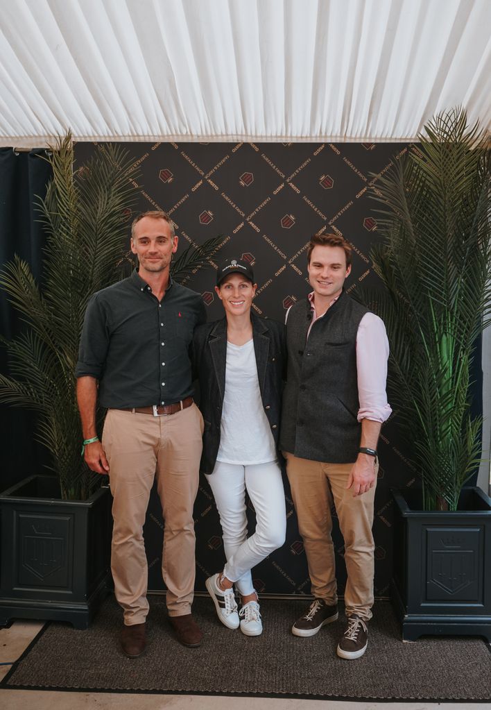 Zara Tindall in a white outfit standing with two men