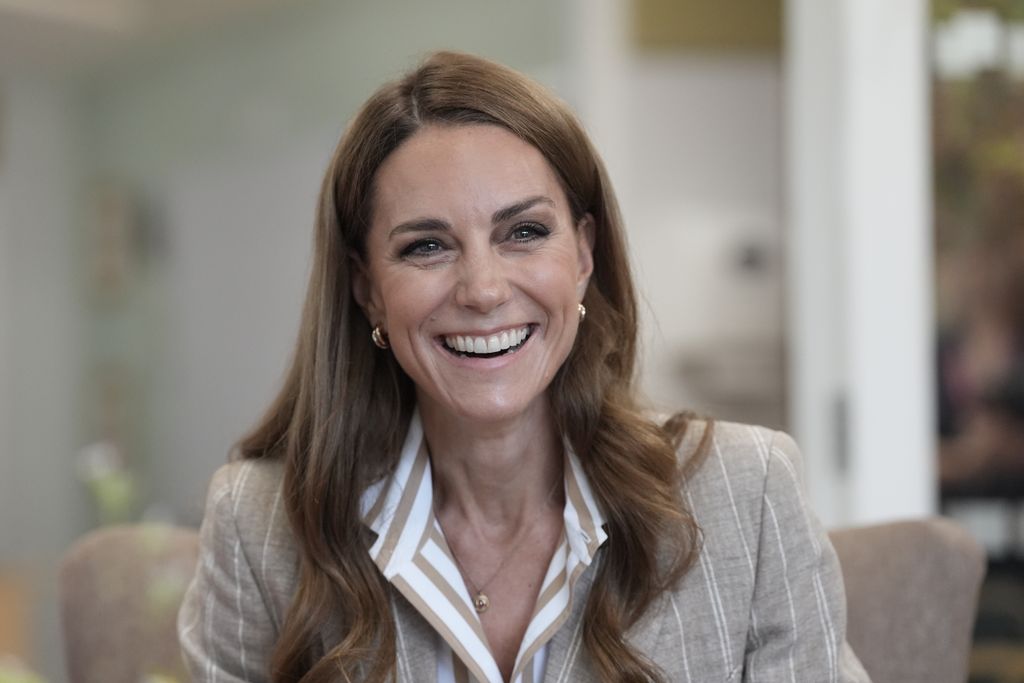Kate Middleton smiling in striped blouse and blazer