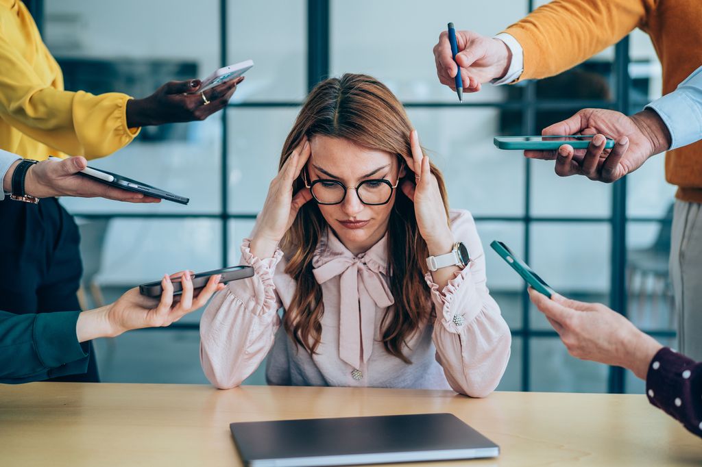 Shot of a stressed out businesswoman surrounded by colleagues needing help. 