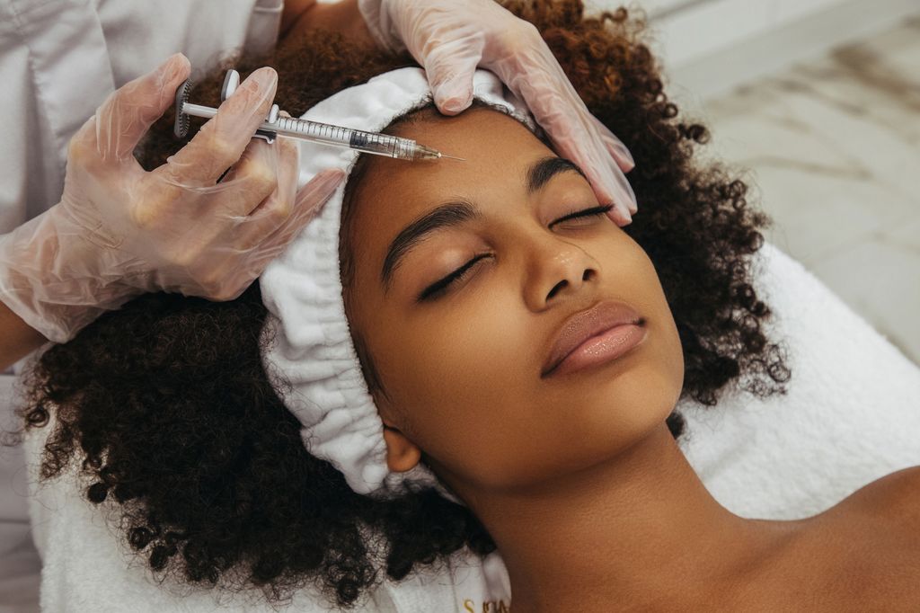 woman lying on a bed having filler injected