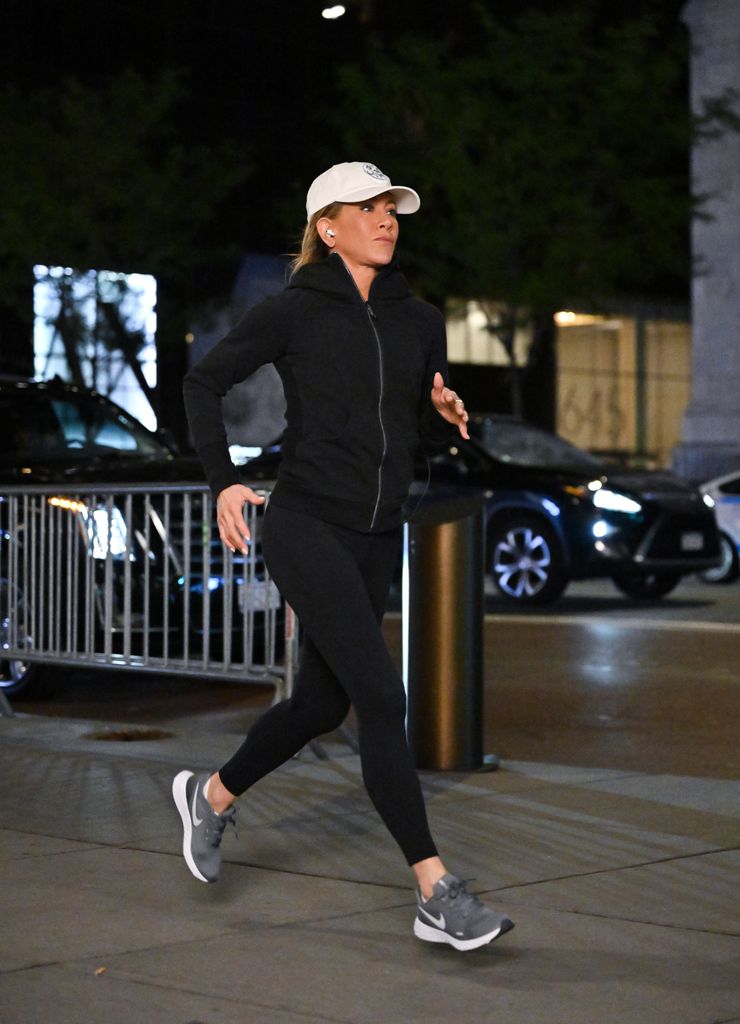 Jennifer Aniston jogging in black leggings and a white cap