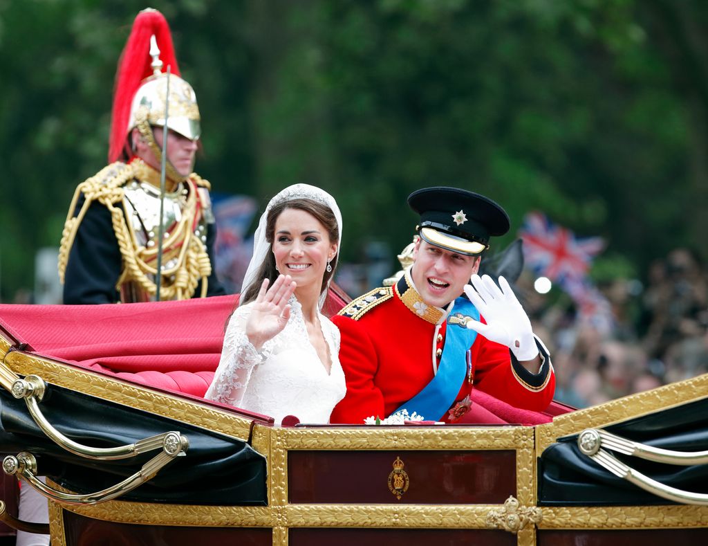 Catherine in bridal gown waving and Prince William (wearing his red tunic uniform of the Irish Guards, of which he is Colonel) travel down The Mall