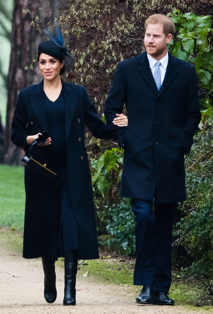 Meghan, Duchess of Sussex in black coat walking with Prince Harry