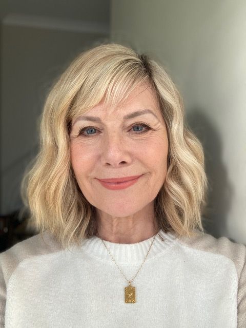 woman smiling for a selfie in a cream top