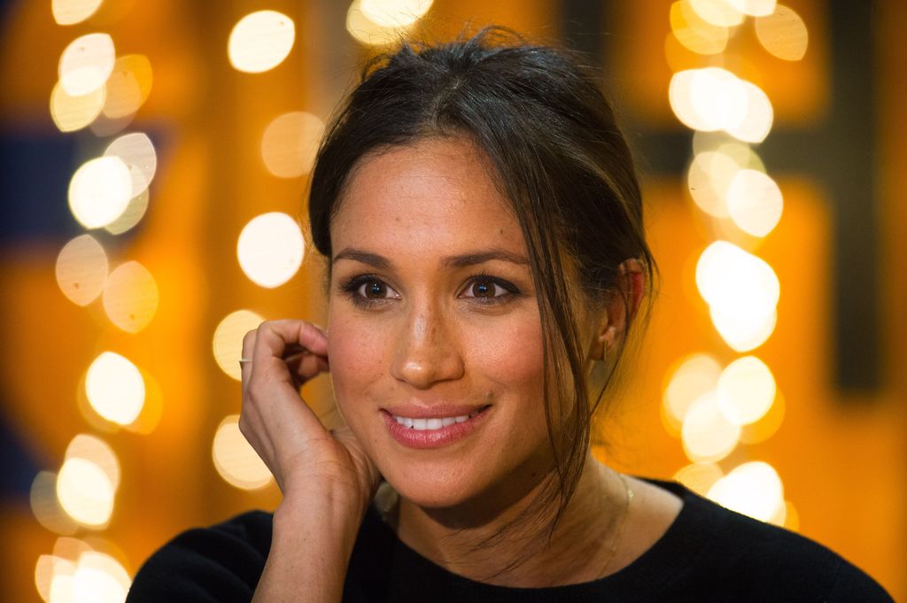 Meghan Markle smiling and touching her hair