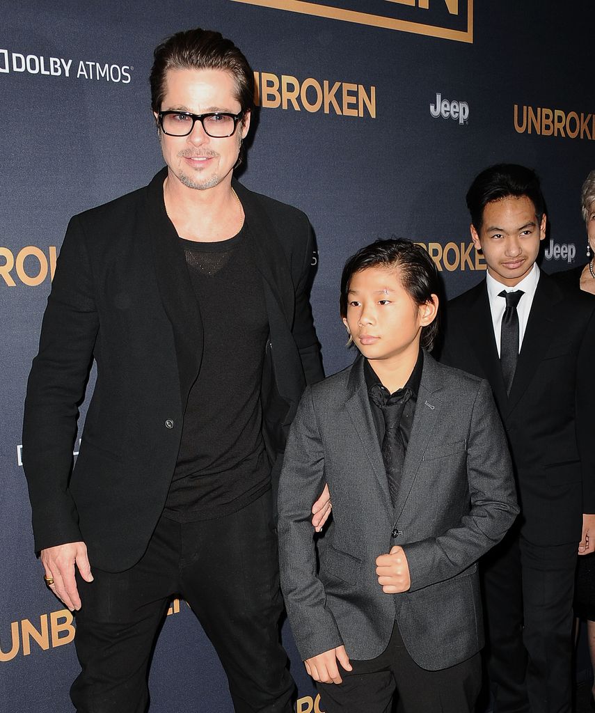 Brad Pitt posing wearing sunglasses stood next to his son Pax Thien Jolie-Pitt who is in a suit