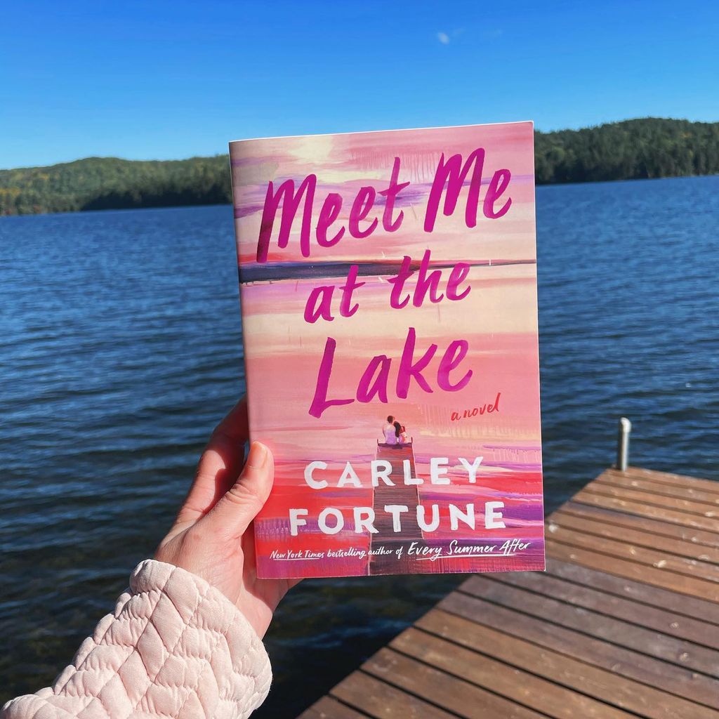 woman holding a book against a lake backdrop