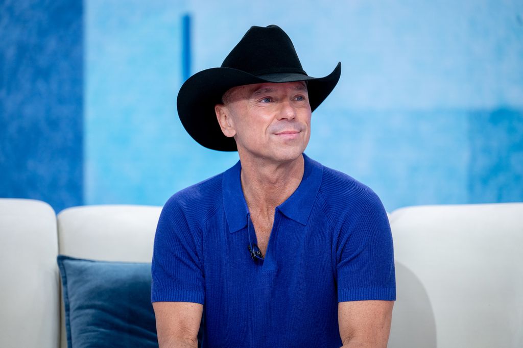 kenny chesney in cowboy hat and blue shirt sitting on a couch