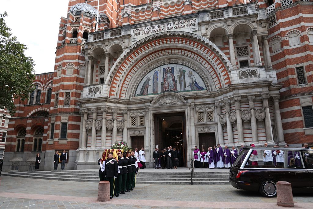 Pallbearers carry the coffin to a hearse following a Requiem Mass, a Catholic funeral service