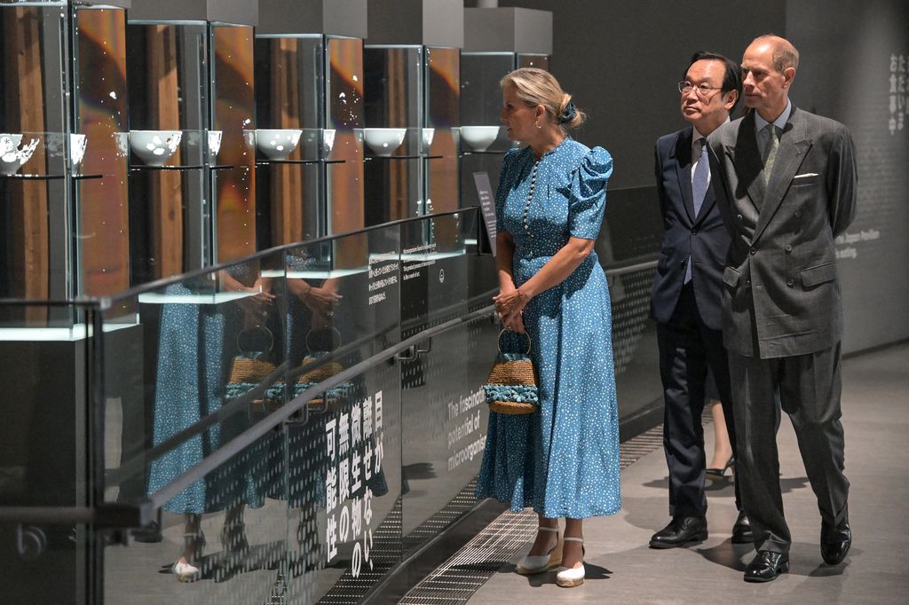 Sophie in blue dress and edward looking at exhibit 