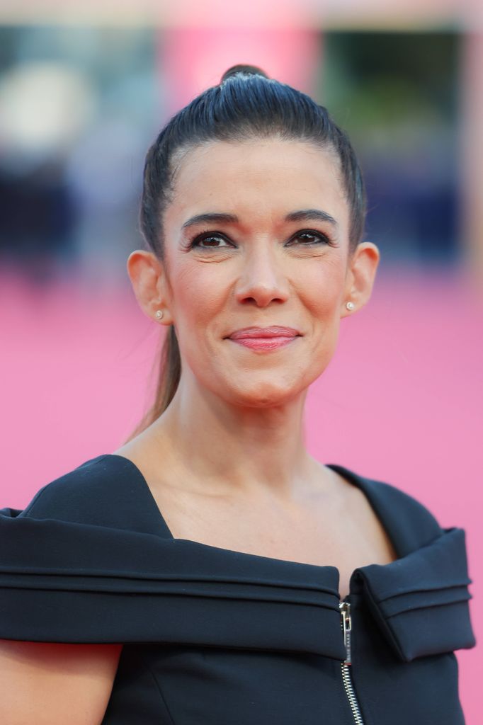 woman in black dress posing on pink carpet