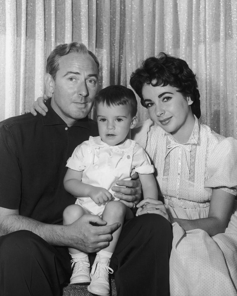 Black-and-white photo of Michael Wilding and Elizabeth Taylor holding a baby boy