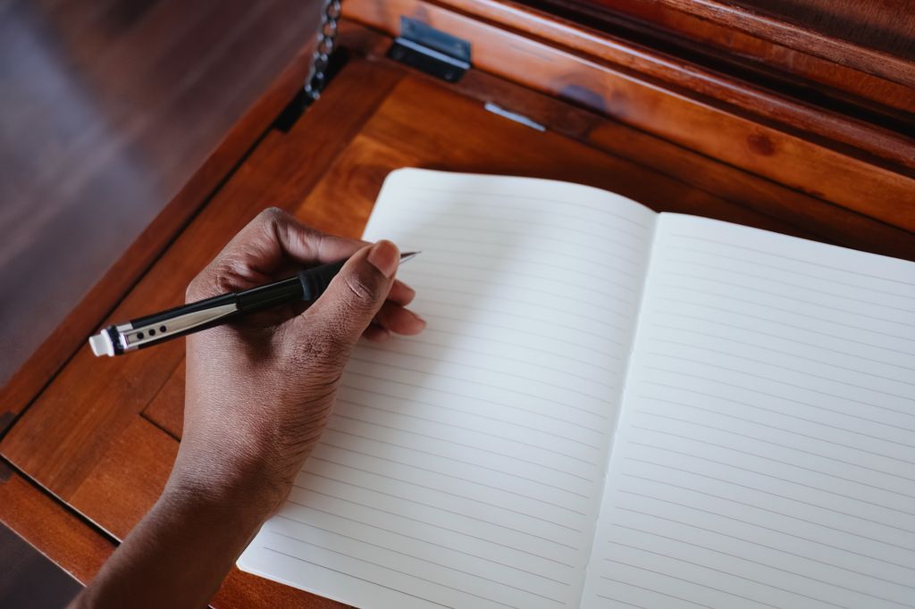 High angle view of unrecognizable black woman preparing to write in empty notebook