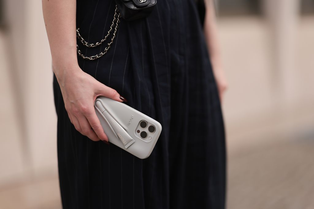 Maria Barteczko seen wearing The Frankie Shop dark blue belted pinstriped oversized pants and Rhode by Hailey Bieber iPhone grey silicon case, on March 31, 2024 in Berlin, Germany