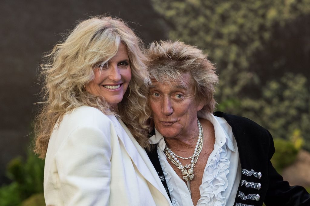 Penny Lancaster in a white blazer smiling with Rod Stewart
