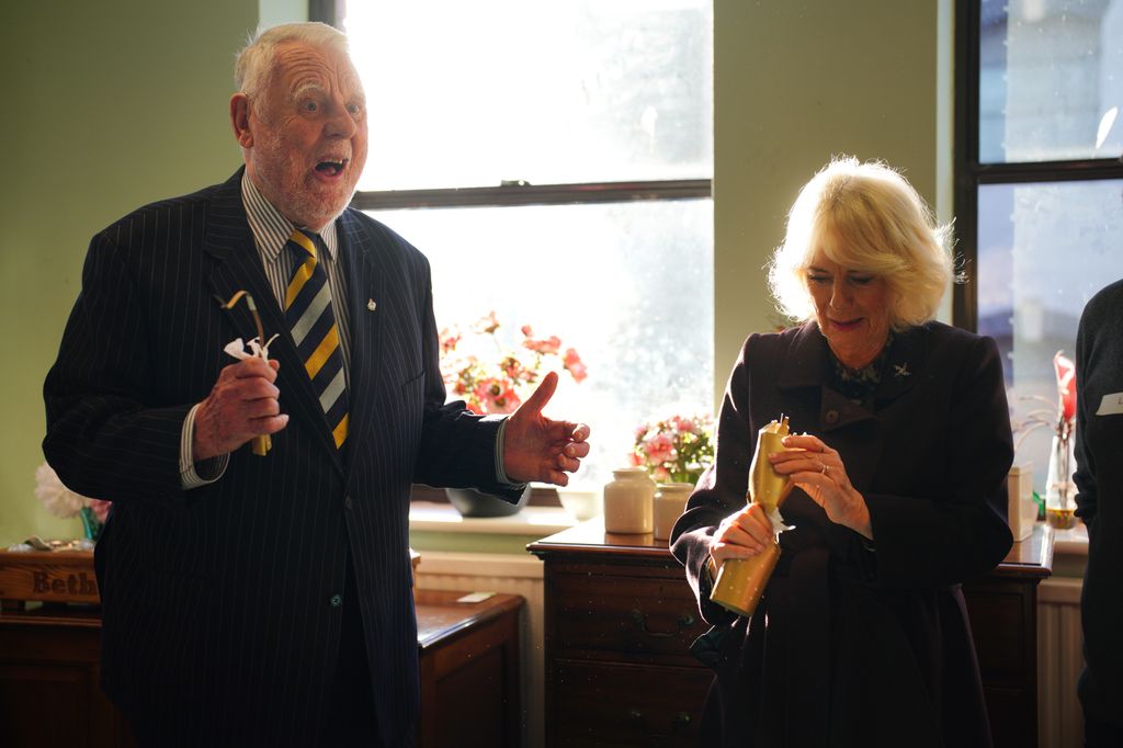 Queen Camilla and Sir Terry Waite after pulling a cracker