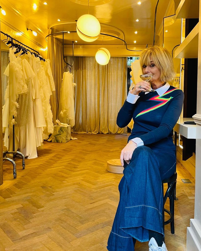 Jane Moore sipping champagne in zig zag print navy jumper 