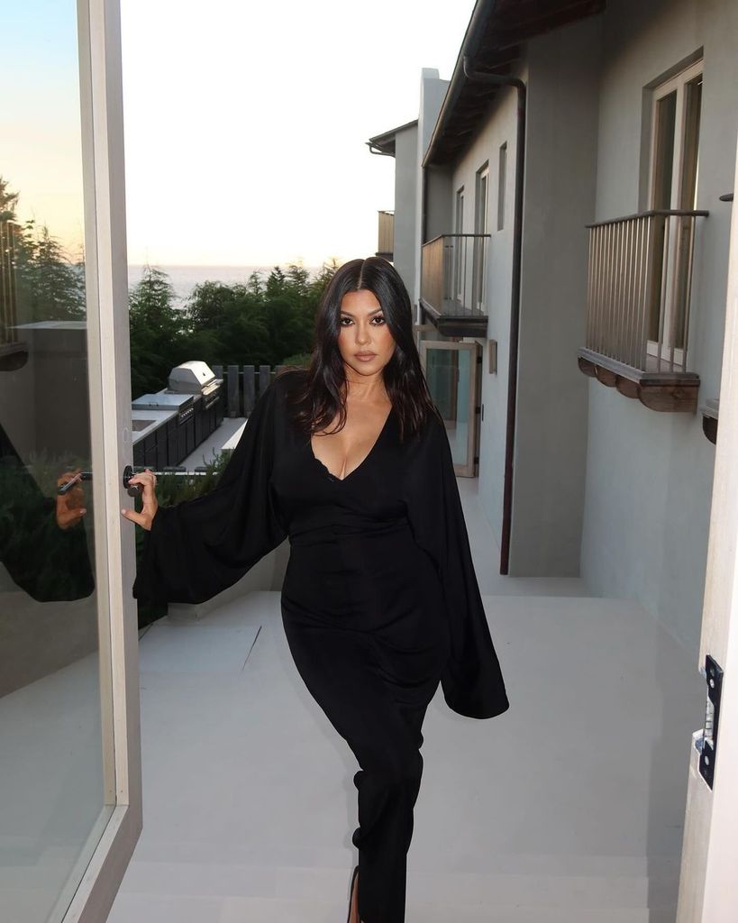 Kourtney Kardashian poses in a Morticia Addams inspired dress outside her LA home in a photo shared on Instagram