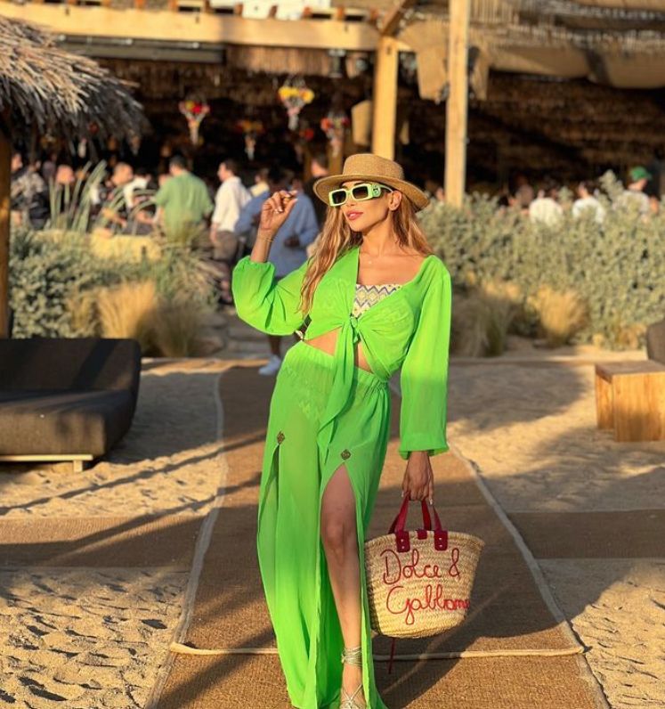 Farah El Kadhi in a green outfit in front of a beachside restaurant