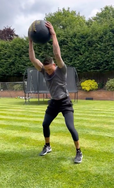 man throwing gym ball in garden with striped lawn