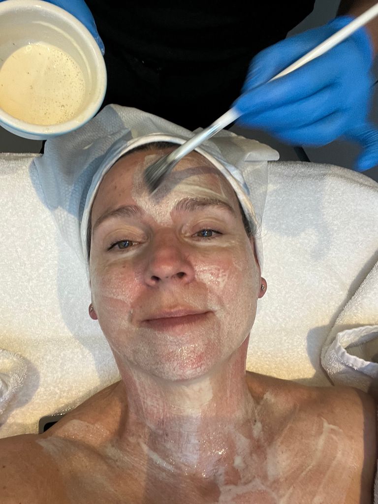 woman lying on a bed having her face painted 
