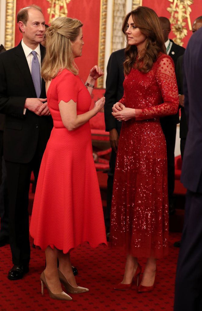 Duchess Sophie and Princess Kate talking to each other at Buckingham palace, both in red dresses