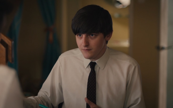Teenager in shirt and tie sitting at kitchen table