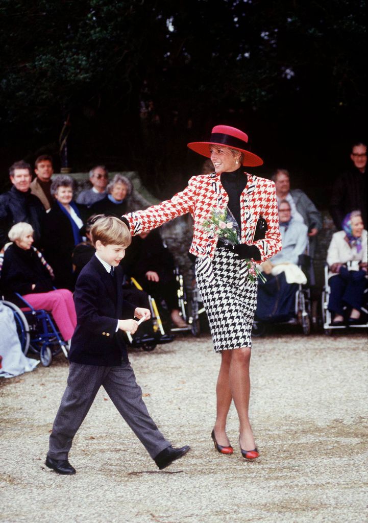 Princess Diana With Prince William walking past a crowd of people. Diana wears a checked two piece with big hat and high heels. William wears a suit. Diana carries a bunch of flowers. 